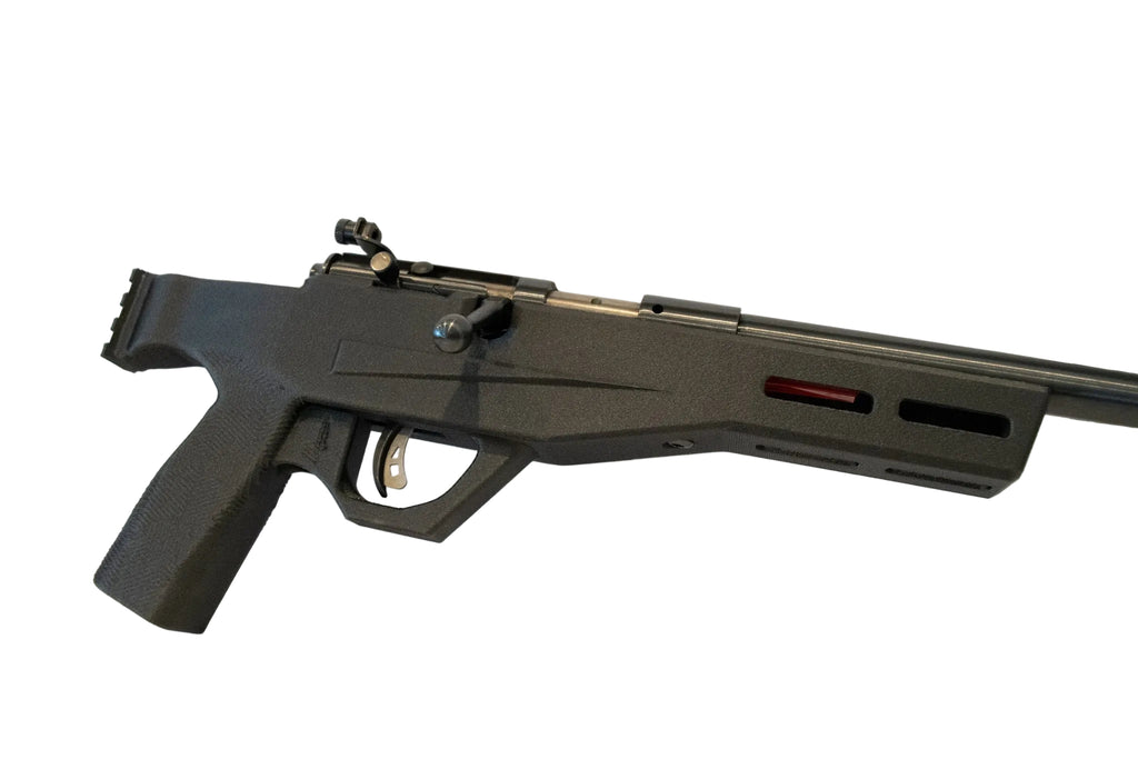 A black tactical-style rifle or airsoft gun with a mounted scope and a red accent on the receiver, displayed on a white surface against a white background.