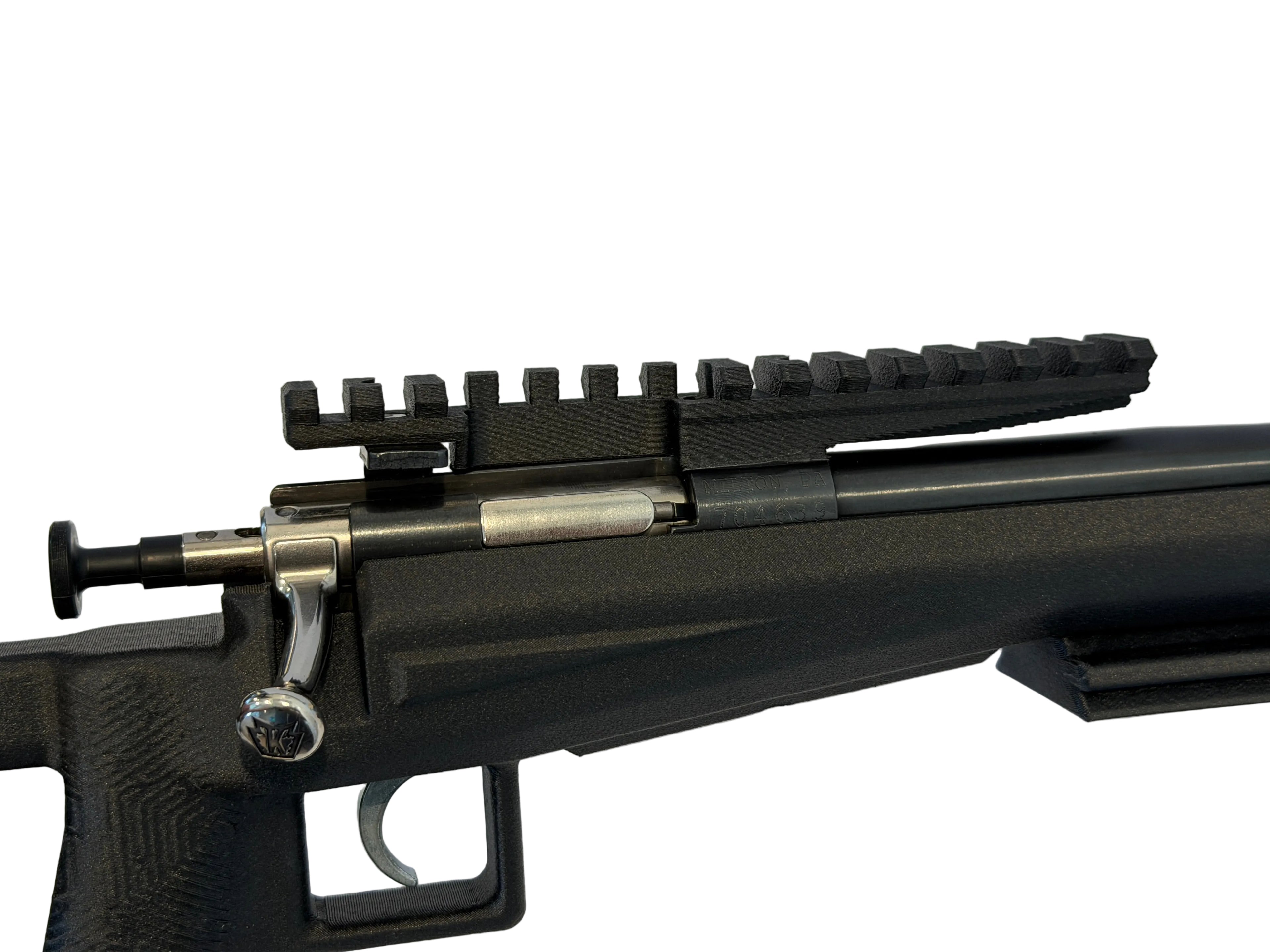 Close-up of a black rifle with a scope rail on a white surface